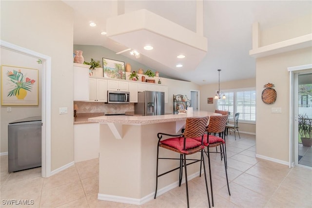 3708 SW 2nd Ln, Cape Coral, FL 33991 - kitchen with appliances with stainless steel finishes, lofted ceiling, a kitchen breakfast bar, white cabinets, and light tile patterned floors