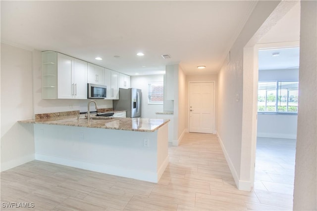 632 Victoria Dr Unit 103, Cape Coral, FL 33904 - kitchen with stainless steel appliances, open shelves, light stone countertops, a peninsula, and white cabinetry