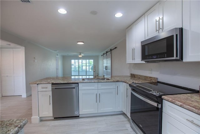 632 Victoria Dr Unit 103, Cape Coral, FL 33904 - kitchen with appliances with stainless steel finishes, a sink, a peninsula, white cabinets, and ornamental molding