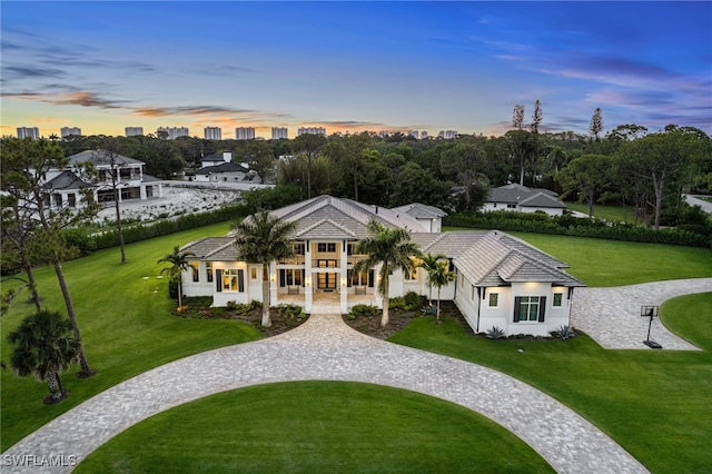 493 Myrtle Rd, Naples, FL 34108 - back of house at dusk featuring a lawn, a tiled roof, curved driveway, and stucco siding