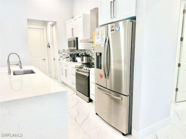 1719 NW 15th St, Cape Coral, FL 33993 - kitchen with stainless steel appliances, a sink, light marble finish floors, white cabinetry, and decorative backsplash