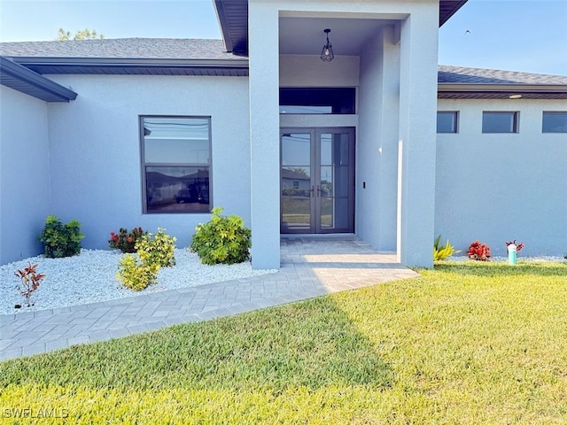 1719 NW 15th St, Cape Coral, FL 33993 - property entrance with french doors, roof with shingles, a yard, and stucco siding