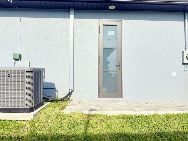 1719 NW 15th St, Cape Coral, FL 33993 - doorway to property with stucco siding and central air condition unit