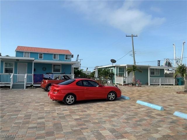 1180 Main St Unit 6, Fort Myers Beach, FL 33931 - view of front of property with uncovered parking, covered porch, and metal roof