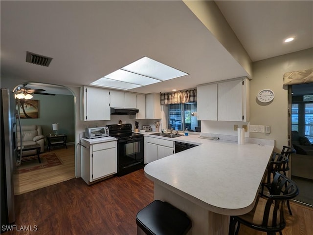 11397 Argentine Ct, Bokeelia, FL 33922 - kitchen featuring black appliances, a peninsula, light countertops, under cabinet range hood, and a kitchen bar