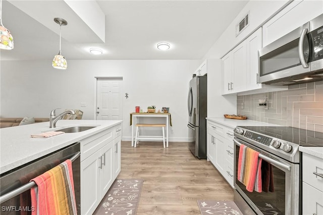 27111 Matheson Ave Unit 103, Bonita Springs, FL 34135 - kitchen with appliances with stainless steel finishes, a sink, decorative backsplash, white cabinetry, and light countertops
