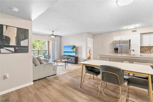 1150 Wildwood Lakes Blvd Unit 203, Naples, FL 34104 - living area featuring light wood-style floors, a textured ceiling, ceiling fan, and baseboards