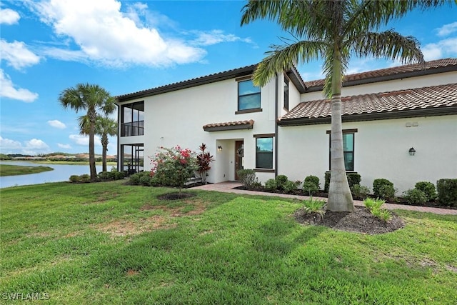 12003 Hawthorn Lake Dr Unit 101, Fort Myers, FL 33913 - view of front of home with a water view, a front lawn, a tiled roof, and stucco siding