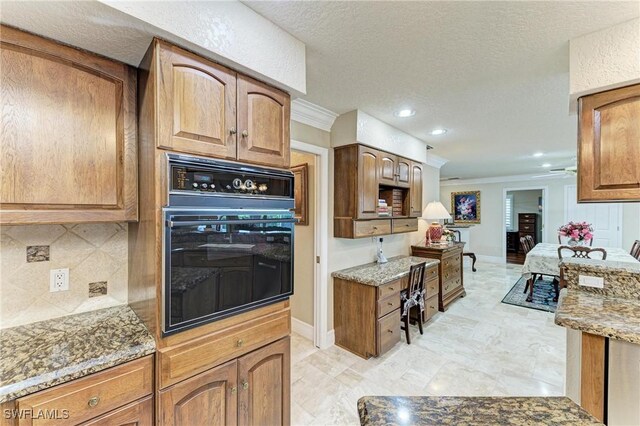 414 Caicos Dr, Punta Gorda, FL 33950 - kitchen featuring black oven, crown molding, light stone countertops, backsplash, and baseboards