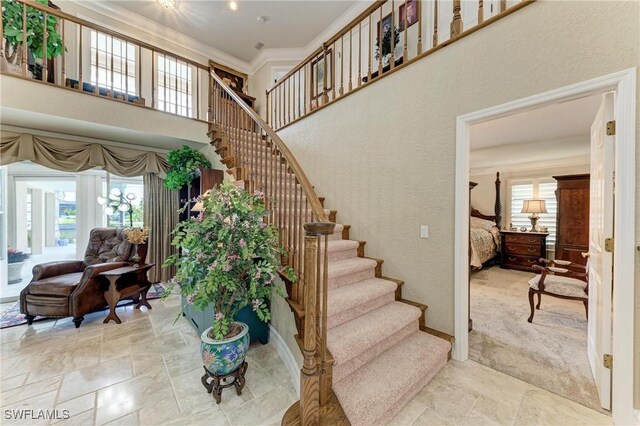 414 Caicos Dr, Punta Gorda, FL 33950 - stairway featuring crown molding, stone finish floors, a high ceiling, a textured wall, and baseboards