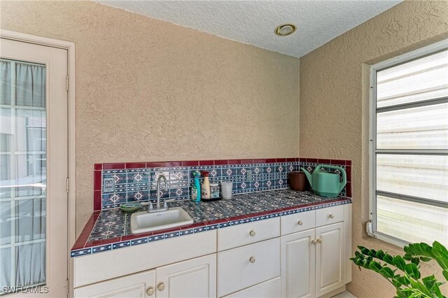 414 Caicos Dr, Punta Gorda, FL 33950 - kitchen featuring a textured wall, a sink, white cabinets, dark countertops, and a textured ceiling