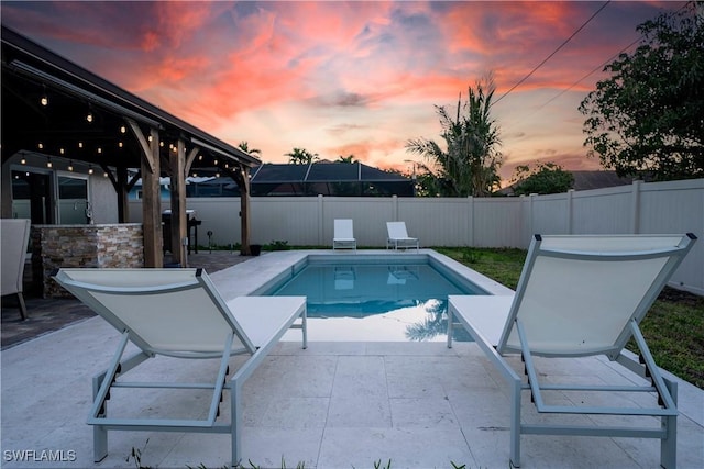 523 107th Ave N, Naples, FL 34108 - pool at dusk featuring a patio and a fenced backyard