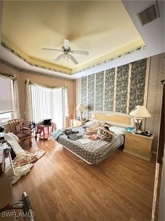 3430 Allegheny Ct, Naples, FL 34120 - bedroom with a raised ceiling, wood finished floors, and ceiling fan
