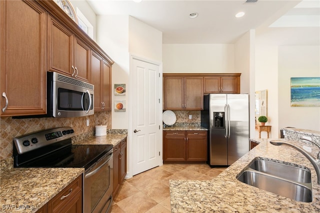 6492 Caldecott Dr, Naples, FL 34113 - kitchen with stainless steel appliances, a sink, decorative backsplash, light stone countertops, and brown cabinets