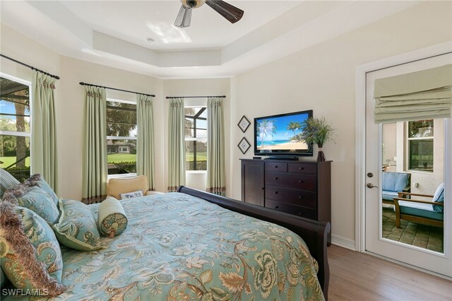 6492 Caldecott Dr, Naples, FL 34113 - bedroom with wood finished floors, a tray ceiling, and a ceiling fan