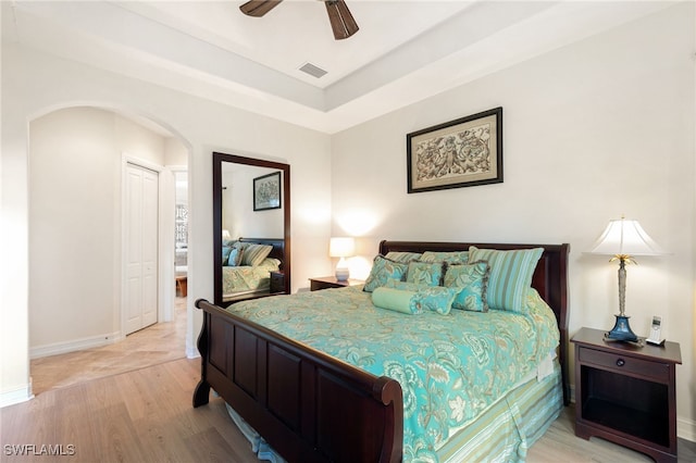6492 Caldecott Dr, Naples, FL 34113 - bedroom with light wood finished floors, arched walkways, baseboards, a ceiling fan, and a raised ceiling