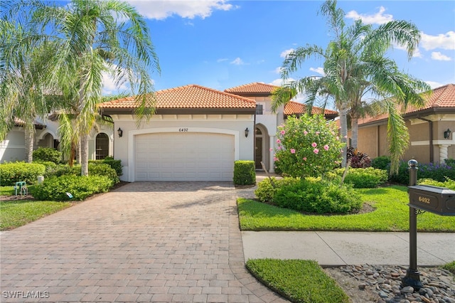 6492 Caldecott Dr, Naples, FL 34113 - mediterranean / spanish-style home with an attached garage, a tiled roof, decorative driveway, and stucco siding