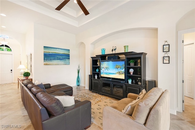 6492 Caldecott Dr, Naples, FL 34113 - living area featuring a ceiling fan, a tray ceiling, arched walkways, and light tile patterned flooring
