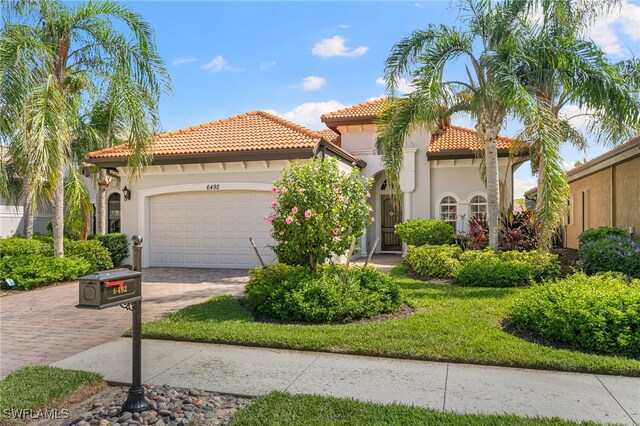 6492 Caldecott Dr, Naples, FL 34113 - mediterranean / spanish-style home with an attached garage, decorative driveway, stucco siding, and a tiled roof