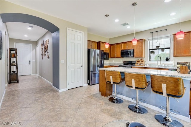 6624 Palmerston Dr, Fort Myers, FL 33966 - kitchen featuring appliances with stainless steel finishes, arched walkways, a kitchen breakfast bar, baseboards, and light stone countertops