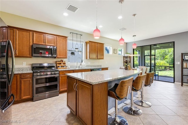 6624 Palmerston Dr, Fort Myers, FL 33966 - kitchen featuring appliances with stainless steel finishes, brown cabinetry, a kitchen island, light stone countertops, and recessed lighting