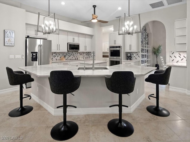 2360 19th St SW, Naples, FL 34117 - kitchen with stainless steel appliances, a sink, arched walkways, backsplash, and a chandelier