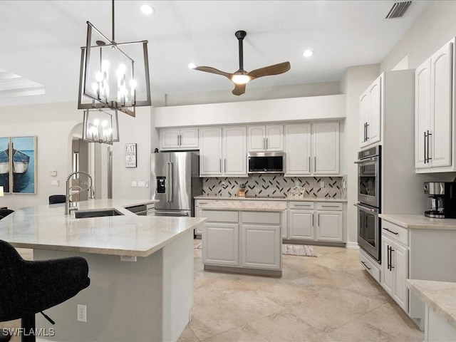 2360 19th St SW, Naples, FL 34117 - kitchen with an island with sink, appliances with stainless steel finishes, a sink, backsplash, and a ceiling fan