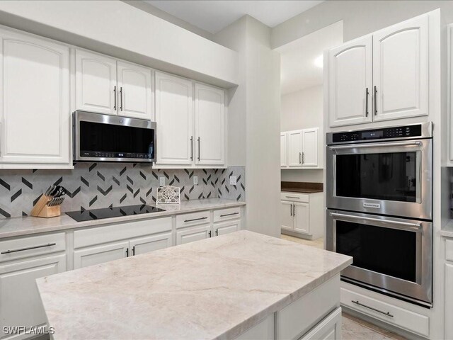 2360 19th St SW, Naples, FL 34117 - kitchen featuring appliances with stainless steel finishes, backsplash, white cabinetry, and light stone countertops