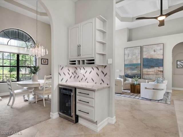 2360 19th St SW, Naples, FL 34117 - bar featuring beverage cooler, a high ceiling, arched walkways, a chandelier, and decorative backsplash