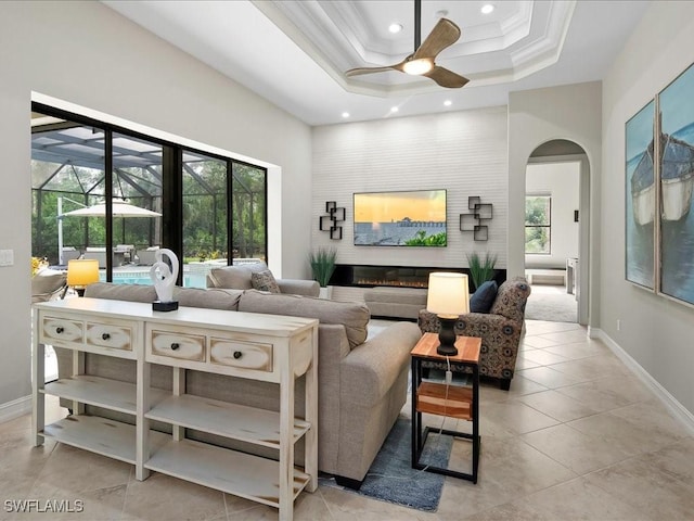 2360 19th St SW, Naples, FL 34117 - living room featuring a ceiling fan, arched walkways, crown molding, recessed lighting, and a glass covered fireplace