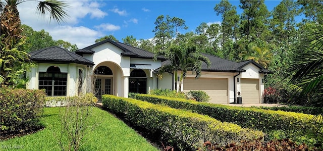 2360 19th St SW, Naples, FL 34117 - view of front of house featuring french doors, an attached garage, stucco siding, and a front yard
