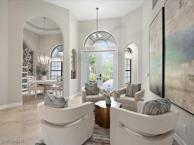 2360 19th St SW, Naples, FL 34117 - tiled living room featuring a chandelier, a high ceiling, baseboards, arched walkways, and french doors