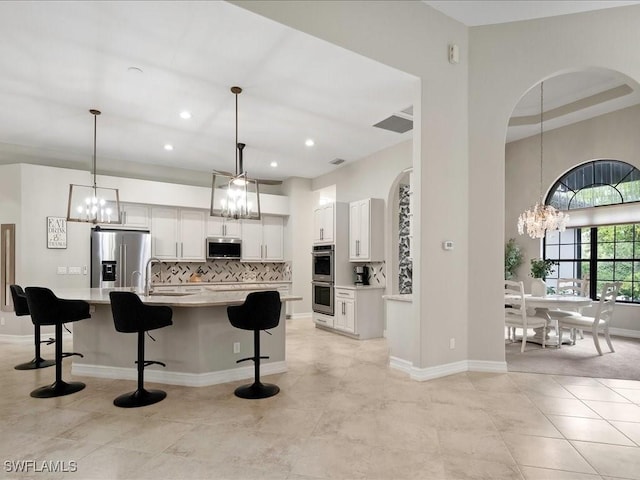 2360 19th St SW, Naples, FL 34117 - kitchen with appliances with stainless steel finishes, a chandelier, light countertops, a breakfast bar area, and tasteful backsplash