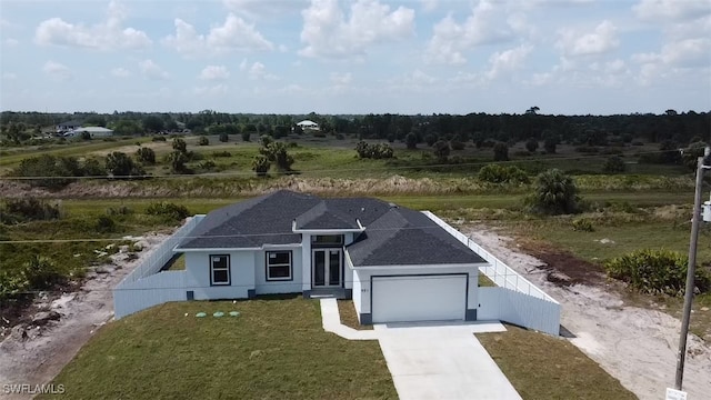 951 Commodore St, Lehigh Acres, FL 33974 - view of front of property featuring concrete driveway, an attached garage, roof with shingles, and a view of rural / pastoral area