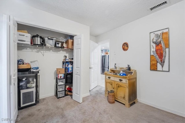 434 Leawood Cir, Naples, FL 34104 - bedroom featuring light carpet, freestanding refrigerator, a closet, a textured ceiling, and baseboards