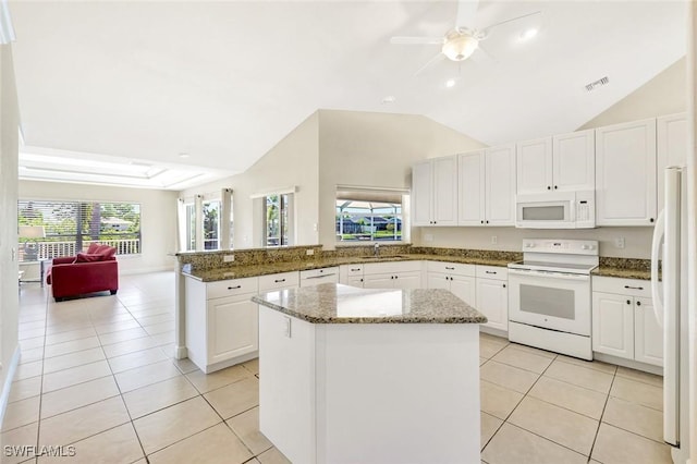 3317 SW 5th Pl, Cape Coral, FL 33914 - kitchen with white appliances, a peninsula, plenty of natural light, light tile patterned floors, and vaulted ceiling