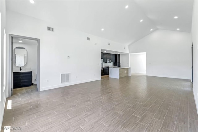 14074 Whittier Ln, Port Charlotte, FL 33981 - unfurnished living room with high vaulted ceiling, light wood-style flooring, and recessed lighting