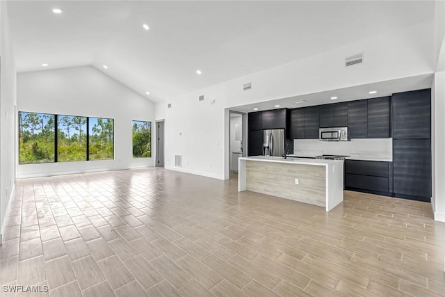 14074 Whittier Ln, Port Charlotte, FL 33981 - kitchen with stainless steel appliances, modern cabinets, open floor plan, dark cabinetry, and high vaulted ceiling