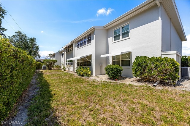 1830 Brantley Rd Unit A2, Fort Myers, FL 33907 - back of property featuring stucco siding, a lawn, and central AC