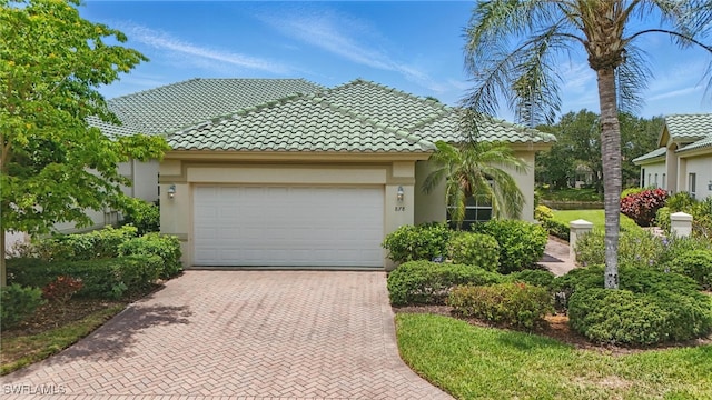 878 Vistana Cir Unit 50, Naples, FL 34119 - view of front of property featuring stucco siding, decorative driveway, an attached garage, and a tiled roof