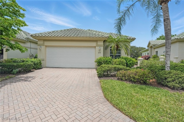878 Vistana Cir Unit 50, Naples, FL 34119 - view of front of house featuring decorative driveway, a tiled roof, stucco siding, and a garage