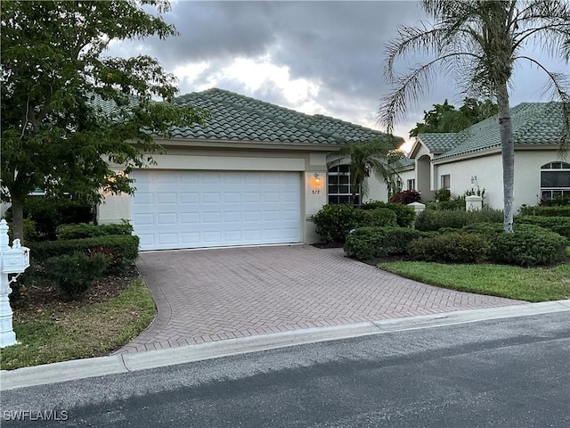 878 Vistana Cir Unit 50, Naples, FL 34119 - view of front facade with decorative driveway, a tile roof, an attached garage, and stucco siding
