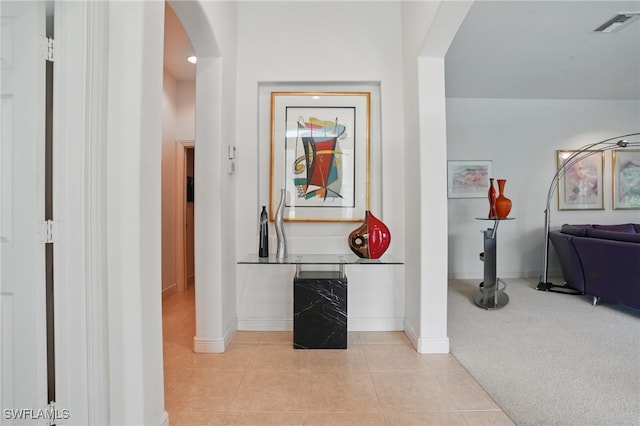 878 Vistana Cir Unit 50, Naples, FL 34119 - corridor with arched walkways, baseboards, light tile patterned floors, and light colored carpet