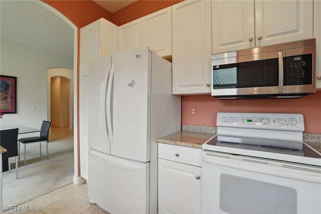 878 Vistana Cir Unit 50, Naples, FL 34119 - kitchen with white appliances, arched walkways, white cabinetry, and light tile patterned flooring