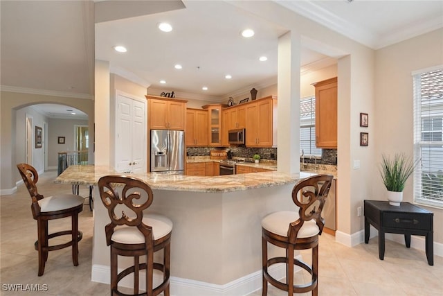 9022 Cascada Way Unit 201, Naples, FL 34114 - kitchen with appliances with stainless steel finishes, arched walkways, ornamental molding, light stone counters, and tasteful backsplash