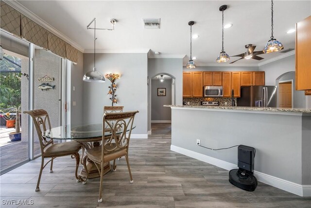 3628 NW 3rd Ter, Cape Coral, FL 33993 - dining area with arched walkways, crown molding, a ceiling fan, baseboards, and wood finished floors
