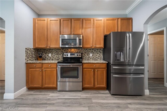 3628 NW 3rd Ter, Cape Coral, FL 33993 - kitchen with stainless steel appliances, arched walkways, ornamental molding, light stone countertops, and tasteful backsplash
