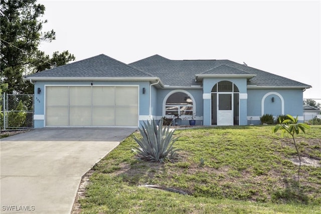 306 Pendleton Ave, Lehigh Acres, FL 33974 - view of front facade featuring stucco siding, an attached garage, driveway, and roof with shingles