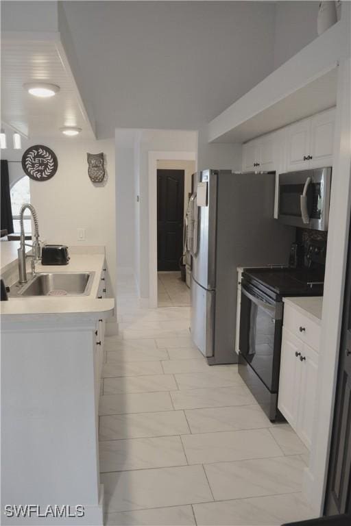 306 Pendleton Ave, Lehigh Acres, FL 33974 - kitchen featuring stainless steel microwave, black range with electric cooktop, a sink, white cabinets, and light countertops