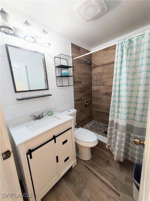 306 Pendleton Ave, Lehigh Acres, FL 33974 - full bath featuring wood finished floors, vanity, a tile shower, and toilet